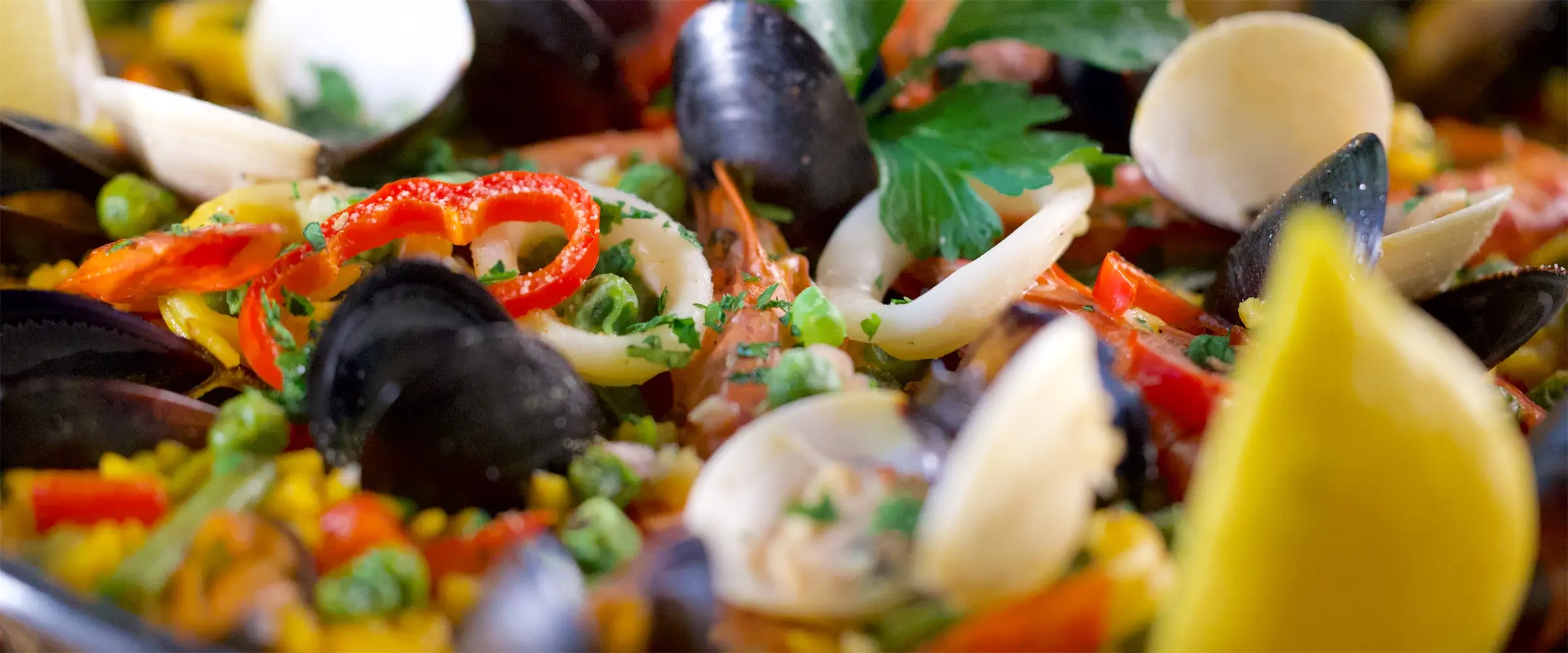 Nahaufnahme einer Paella mit Muscheln, Garnelen und Zitrone